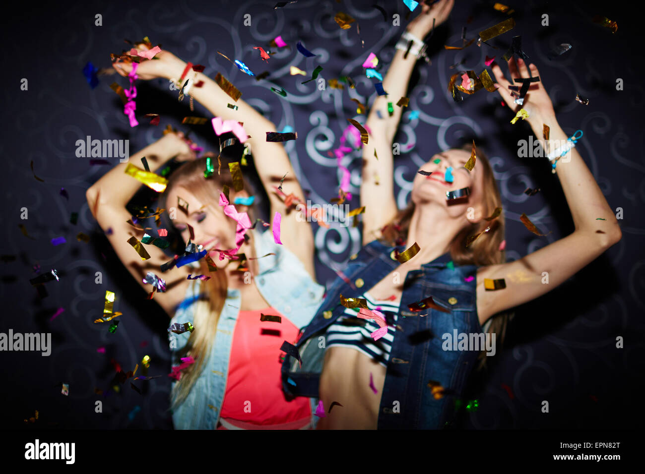 Zwei energetische Mädchen tanzen in Konfetti fallen Stockfoto