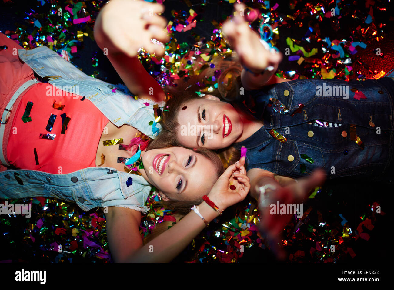 Zwei energetische Mädchen mit erhobenen Armen Blick in die Kamera in Nachtclub Stockfoto