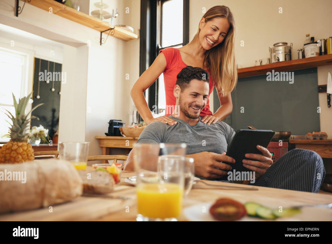 Schuss von glücklicher junger Mann und Frau mit digital-Tablette morgens. Paar mit Touchpad in Küche lächelnd. Stockfoto