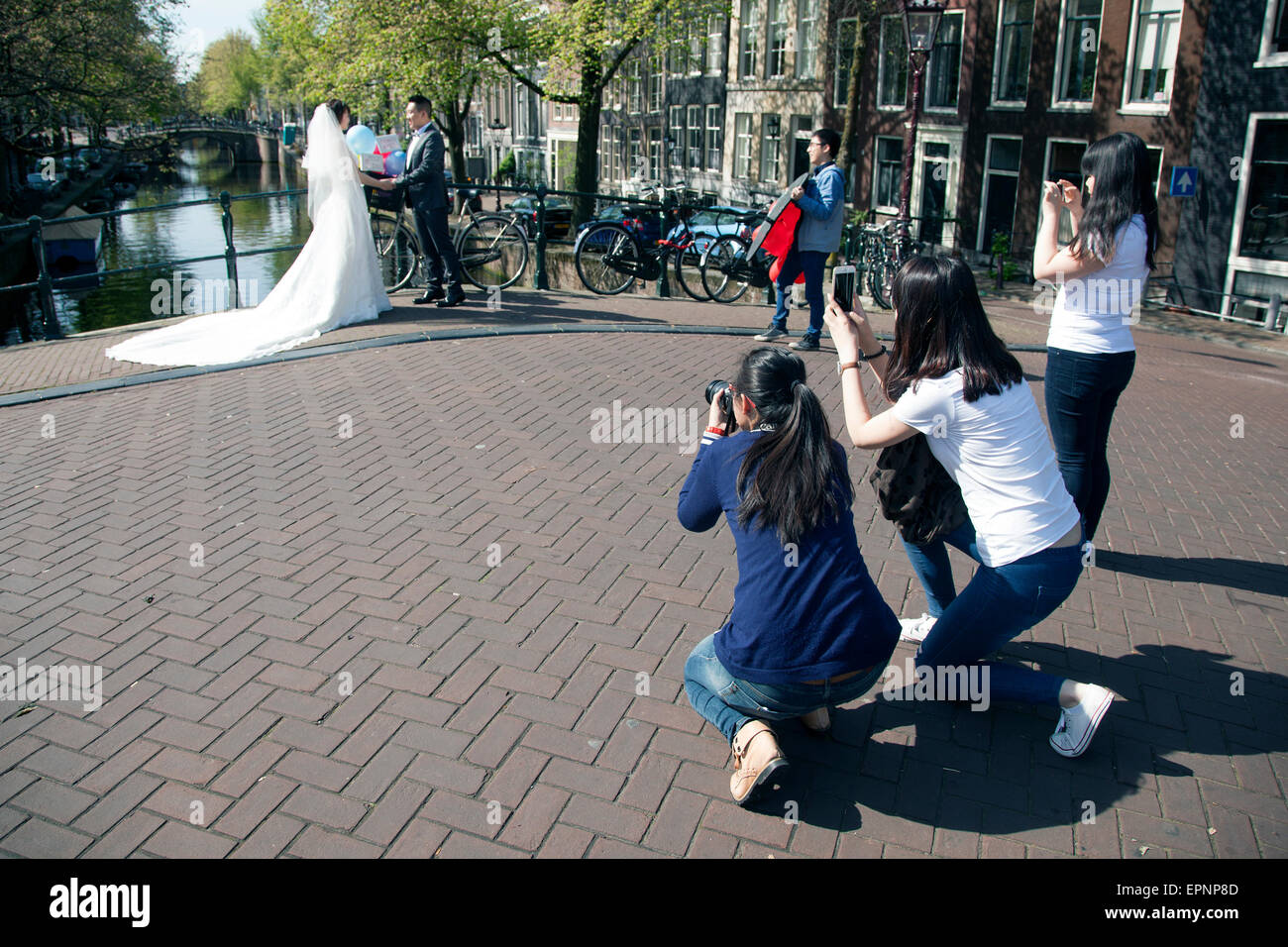 chinesische Braut und Bräutigam werden auf Brücke über Amsterdam Canal fotografiert. Stockfoto