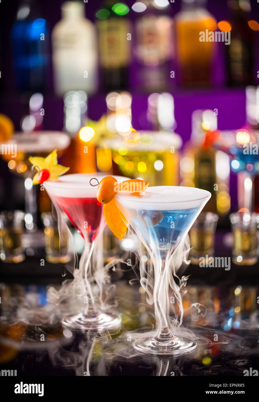 MartiniGetränke mit Trockeneis RauchEffekt, serviert auf Bartheke mit Unschärfe Flaschen auf