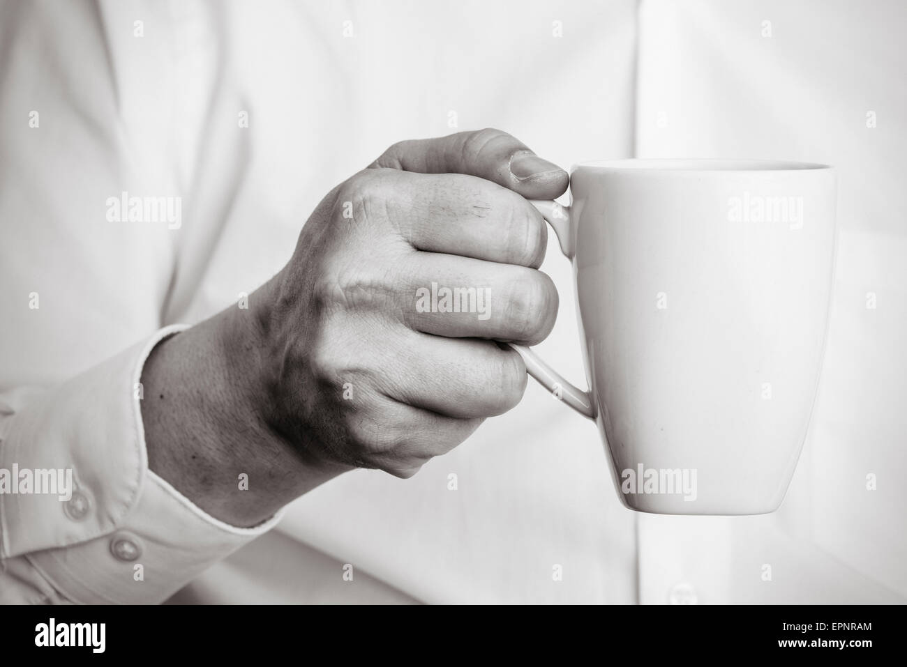 Nahaufnahme der Mann, der eine weiße Kaffeetasse mit seiner Hand hält. Stockfoto