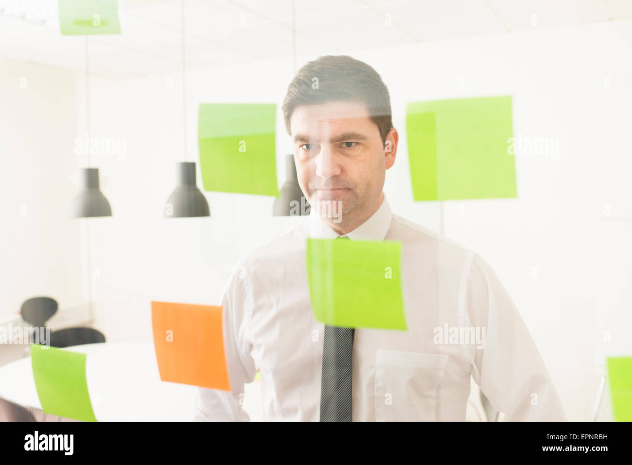 Geschäftsmann Glaswand mit Klebstoff Notizen zu betrachten. Konzeptbild von Business-Planung und Strategie. Stockfoto