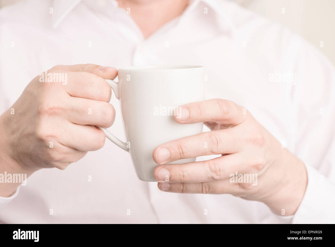 Nahaufnahme der Mann, der eine weiße Kaffeetasse mit seinen Händen hält. Stockfoto