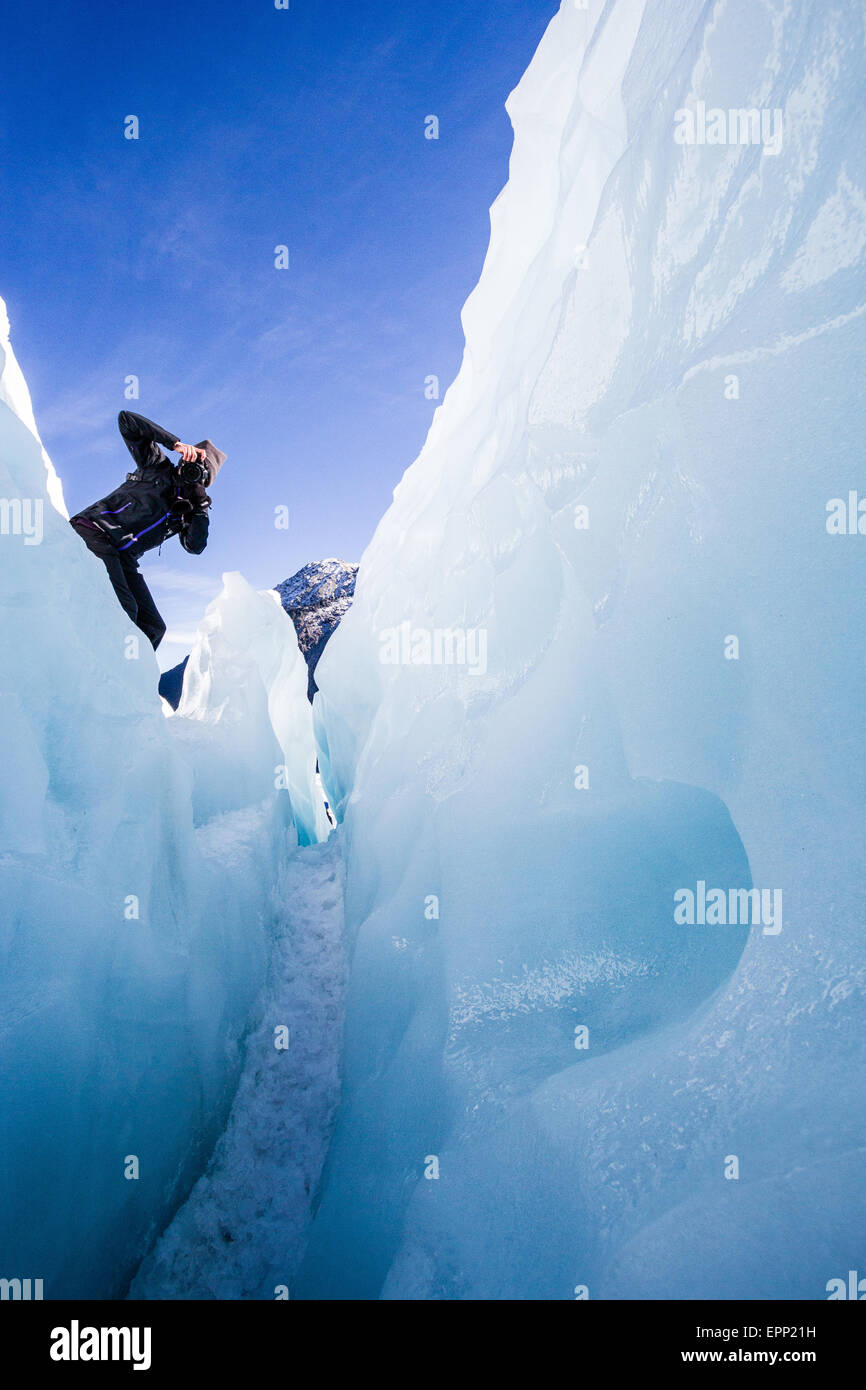 Eine Frau zeigt eine Kamera in eine tiefe Spalte im Eis der Fox-Gletscher in der Südalpen Neuseelands Stockfoto