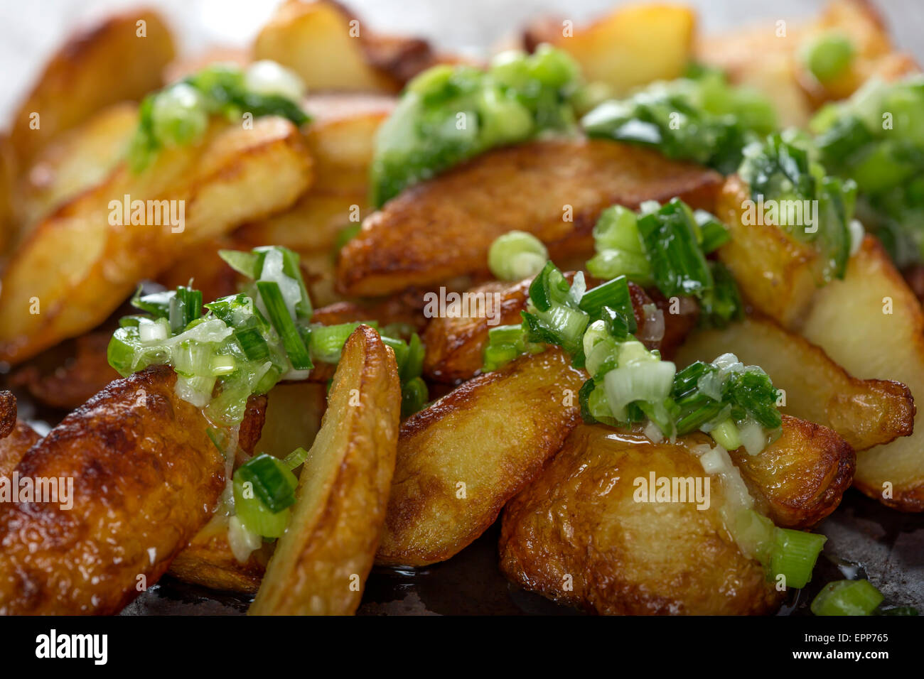Frische hausgemachte knusprig gebratene Kartoffel Wedges mit grünem Knoblauch Stockfoto