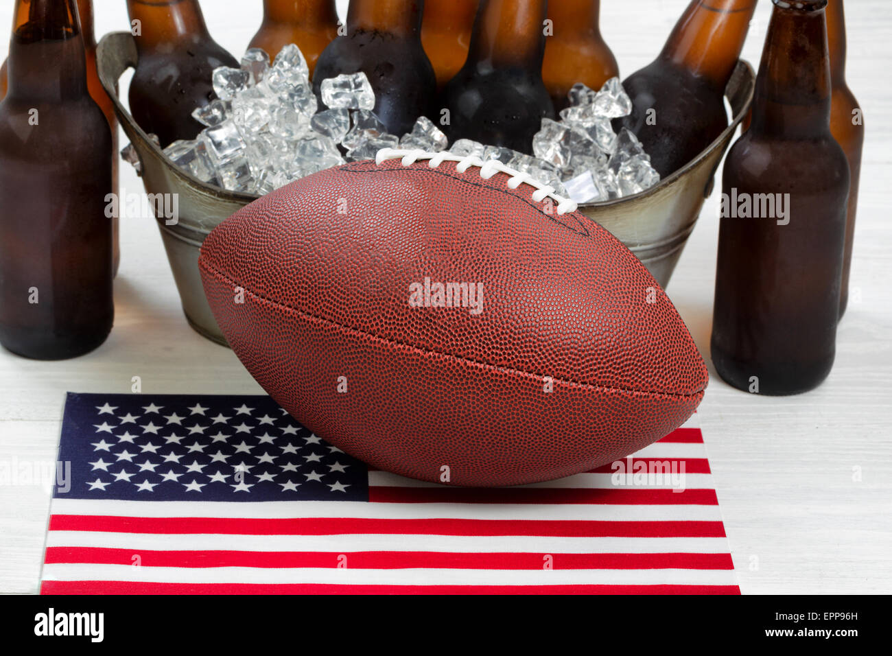 Nahaufnahme des American Football, eiskalten Bier im Eimer und Fahne mit rustikalen weiße Holz darunter. Stockfoto