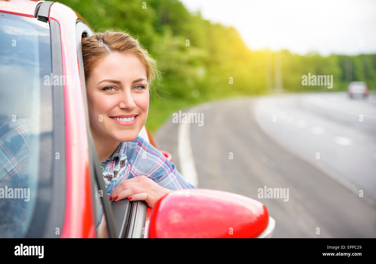 Glücklich lächelnde Mädchen in einem roten Auto. Bei Sonnenuntergang. Reisekonzept. Stockfoto