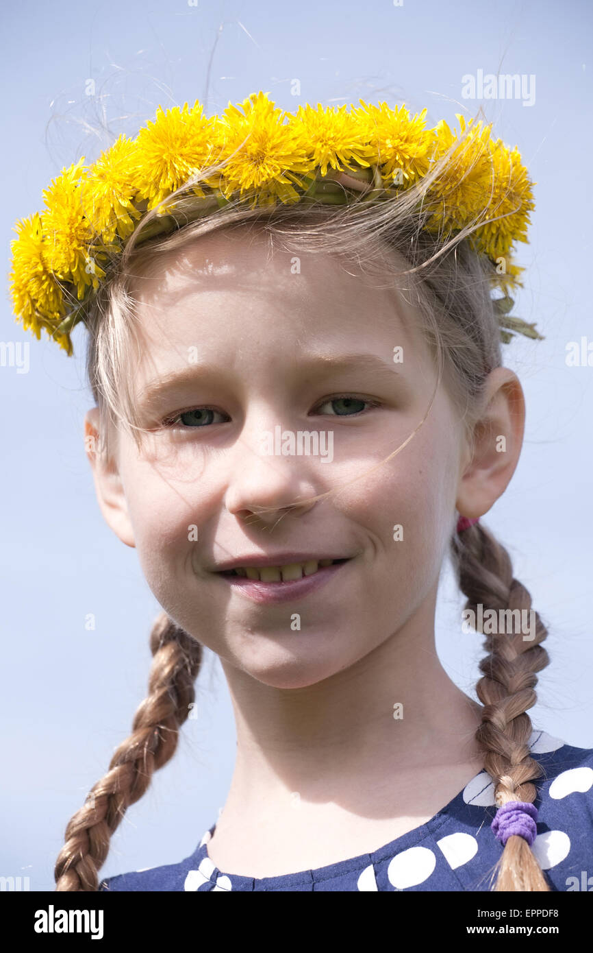 junges Mädchen Porträt in gelber Löwenzahn Kranz auf blauen Himmelshintergrund Stockfoto