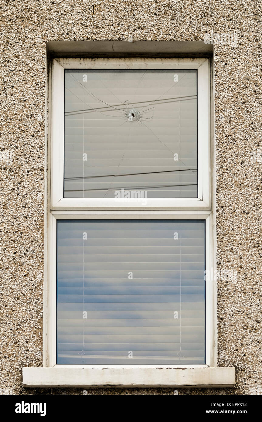 Einschussloch nach einer Waffe Angriff auf ein Haus in einem Fenster links Stockfoto
