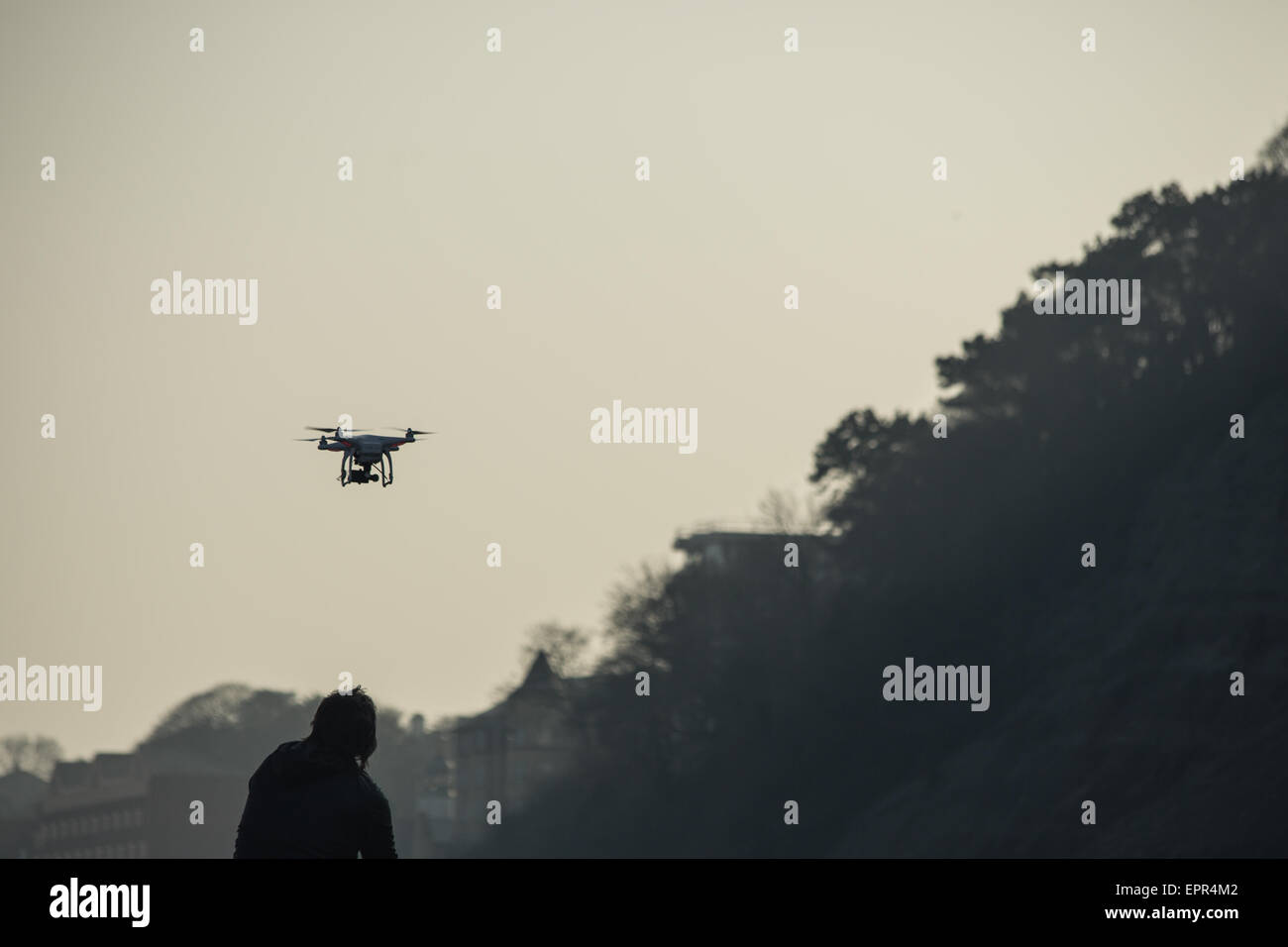 Silhouette des Mannes, die Drohne über Klippen in den Sonnenuntergang fliegen Stockfoto