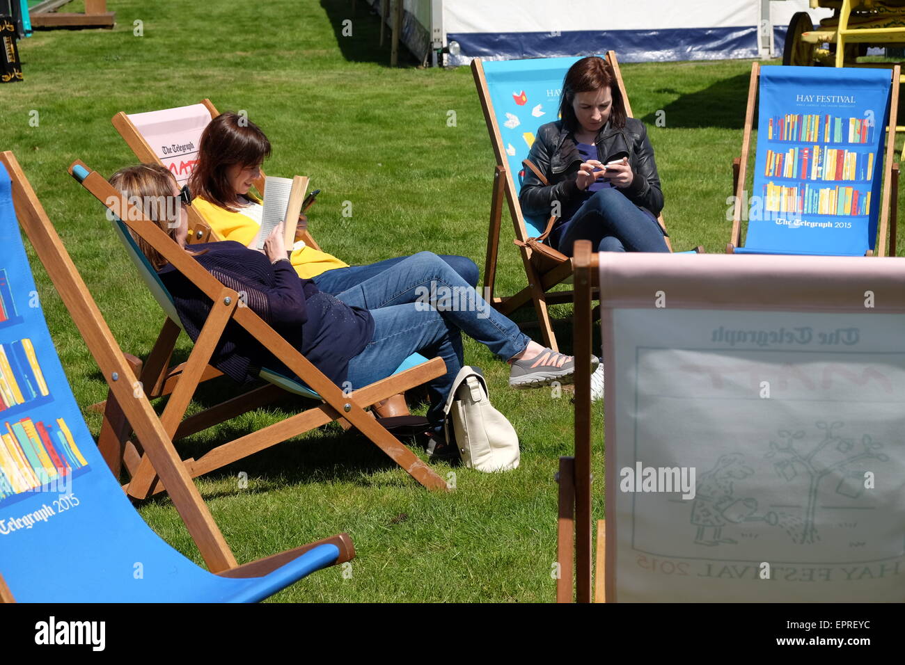 Powys, Wales, UK. 21. Mai 2015. Eröffnungstag für 2015 Hay Festival.  Besucher der Hay Festival genießen Sie die Sonne und nehmen Sie sich Zeit zum sitzen und lesen auf den Festival-Liegestühlen. Stockfoto