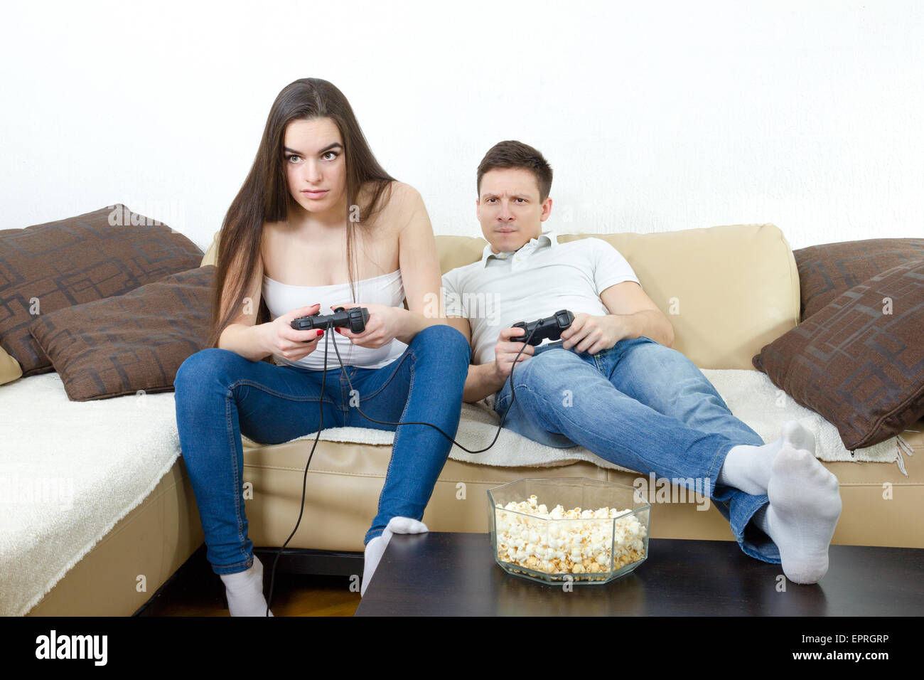 Junge Paar im Wohnzimmer sitzen und spielen Videospiele auf Konsole oder pc mit Joysticks während der Suche im Bildschirm oder Fernseher. Lifestyl Stockfoto