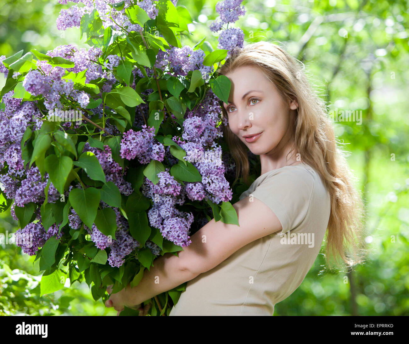 glückliche junge Frau im Park mit einem großen Blumenstrauß ein lila Stockfoto