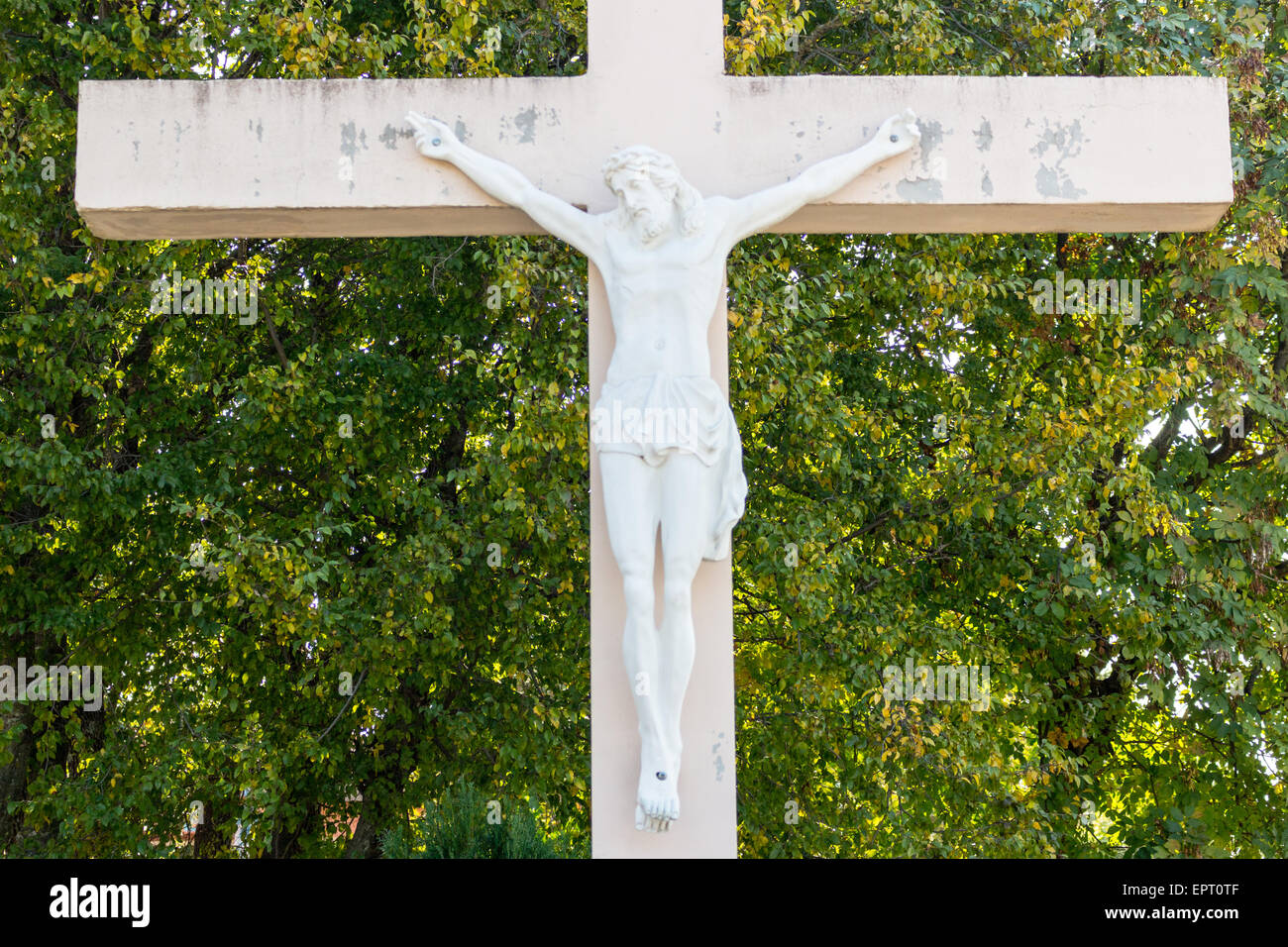 Das große hölzerne weiße Kreuz mit dem gekreuzigten Jesus Christus-Statue am Erscheinung Mountain in Medugorje unter grünen Bäumen und Unkraut Stockfoto