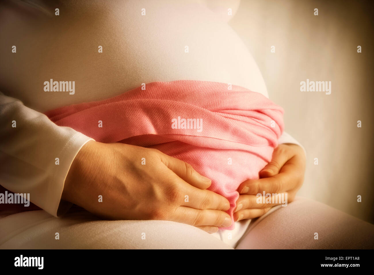 Schwangere Frau in weißen Kleidern und rosa Schal hält ihr Baby-Bauch Stockfoto