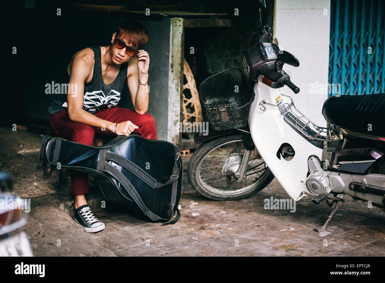 Asiatische Mode Straße Teenager in der Sonnenbrille mit Gitarrenkoffer und Motorrad Stockfoto