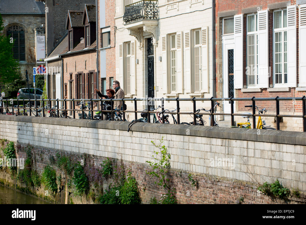Zwei Menschen stehen am Wasser in einer malerischen Straße mit Gebäuden im Hintergrund Stockfoto