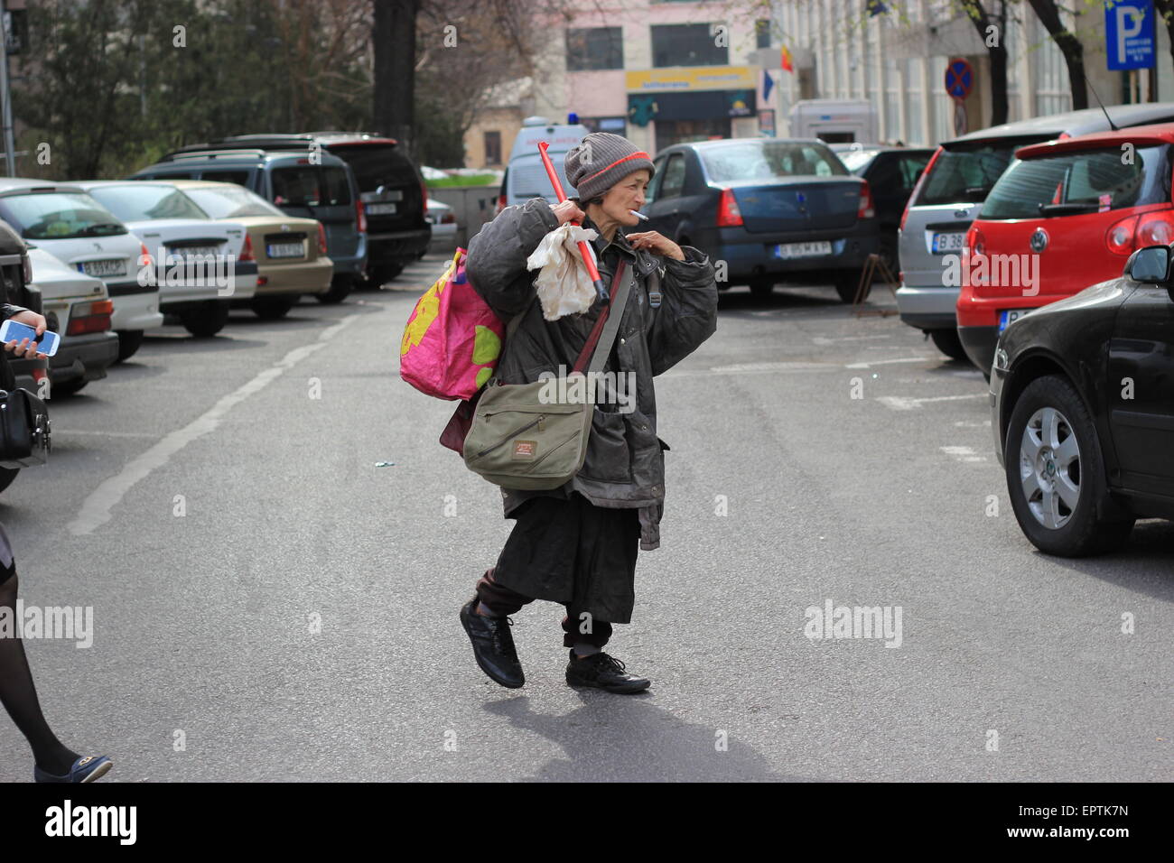 Alte Frau zu Fuß auf einer Straße rauchen, Bukarest, Rumänien Stockfoto