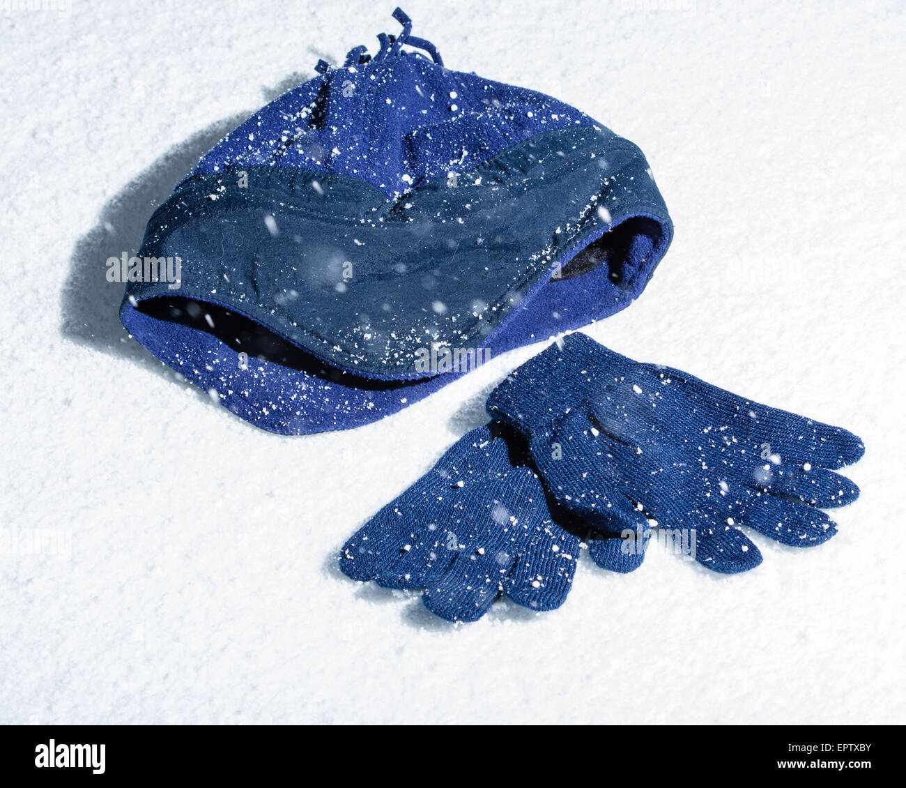 Ein blauer Strickmütze mit passenden Handschuhen im Schnee Stockfoto