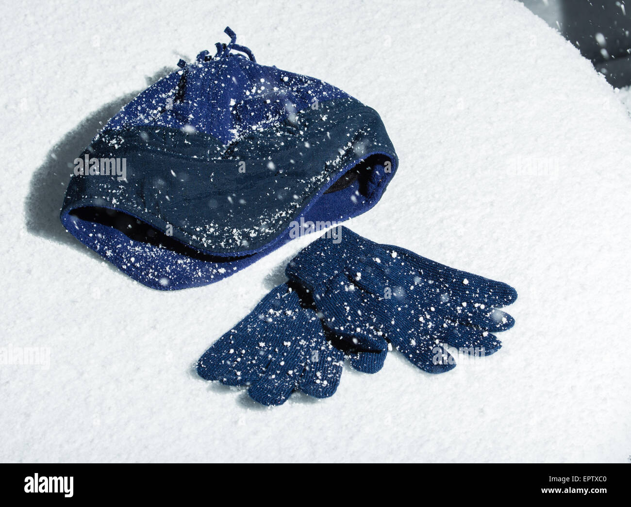 Eine gestrickte Mütze mit passenden Handschuhen im Schnee Stockfoto