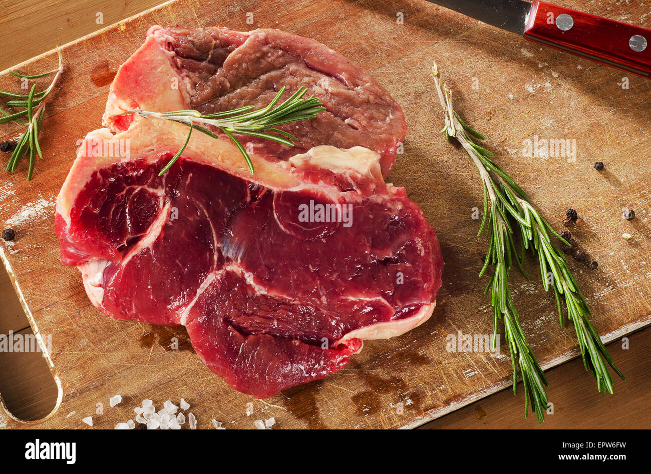 Rohes Steak mit Gewürzen und frischen Kräutern auf Holzbrett. Selektiven Fokus Stockfoto