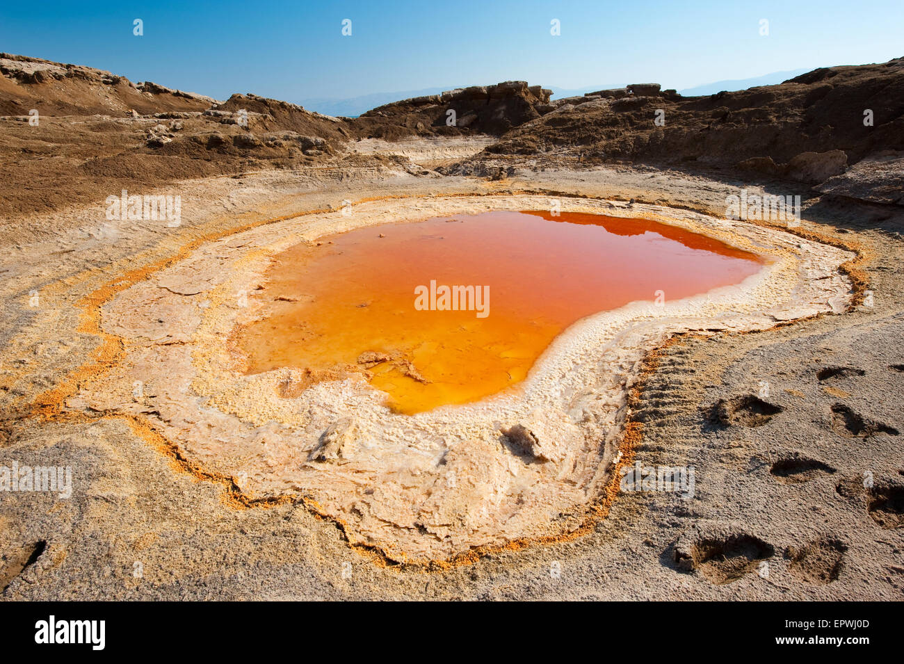 Doline oder Tagebau mit orange Salzwasser am Ufer des Toten Meeres am Ende des Sommers der Wasserstand im wird Stockfoto