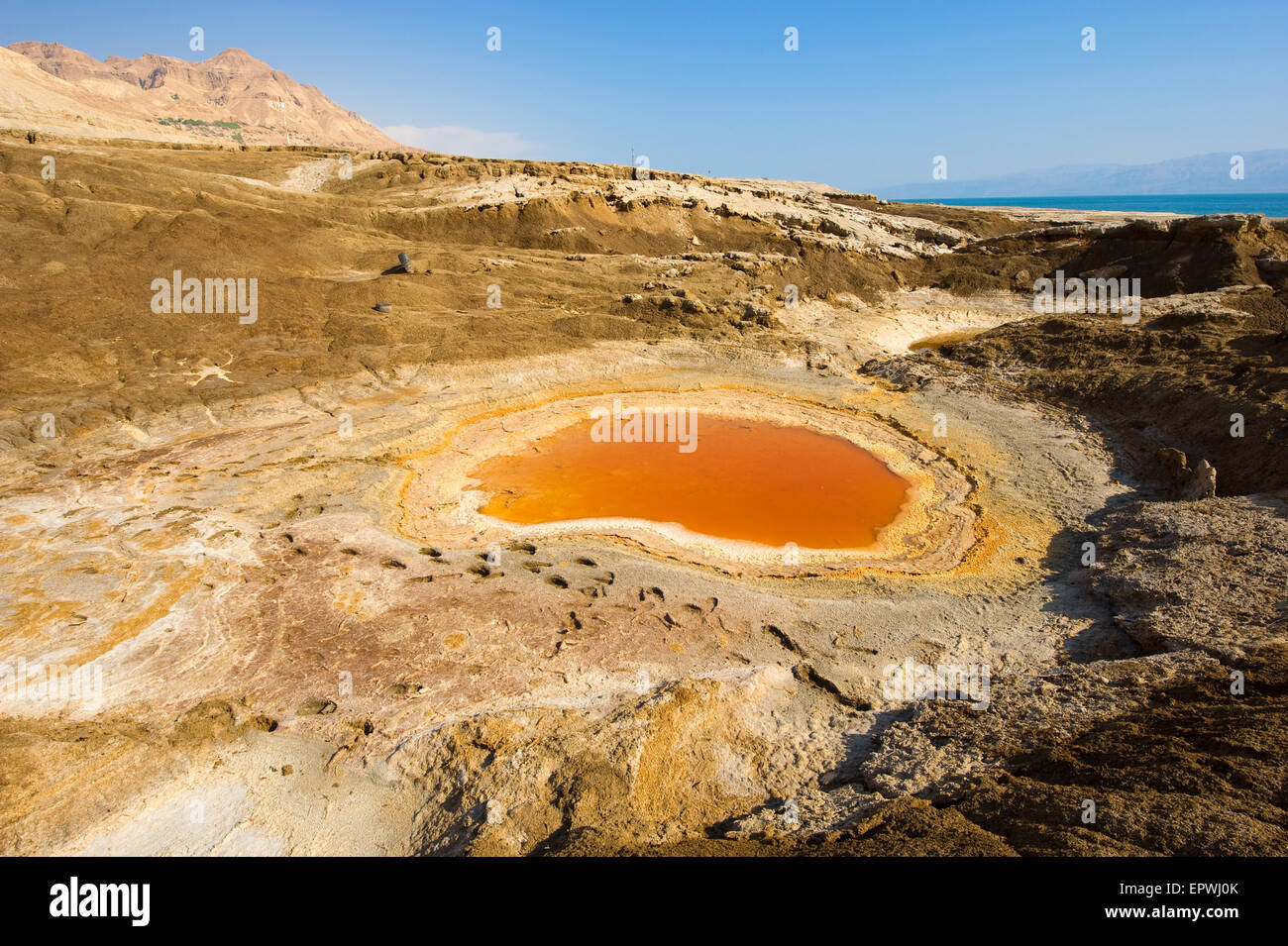 Doline oder Tagebau mit orange Salzwasser am Ufer des Toten Meeres am Ende des Sommers der Wasserstand im wird Stockfoto
