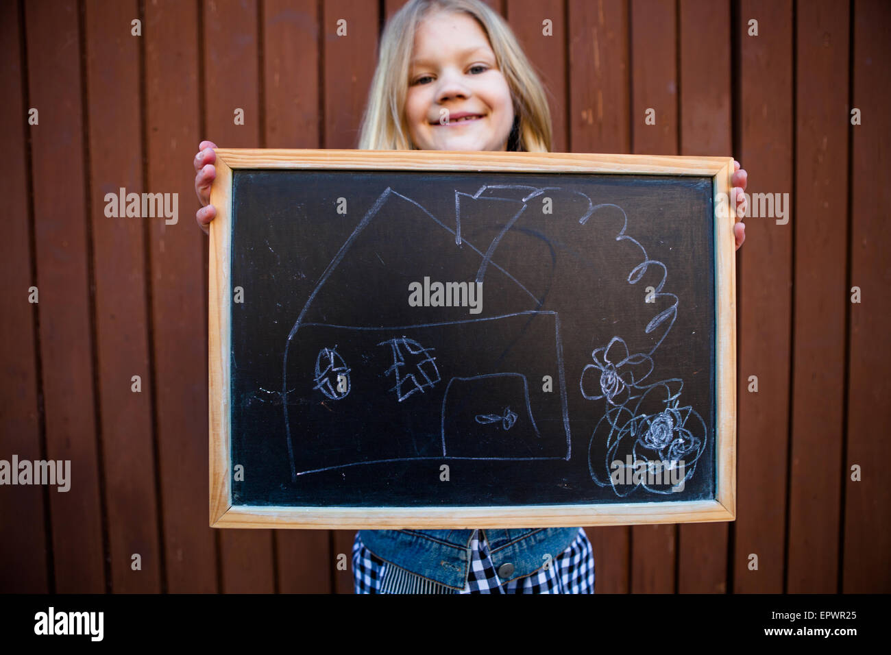 Mädchen hält eine Tafel mit einem Bild von einem Haus drauf Stockfoto