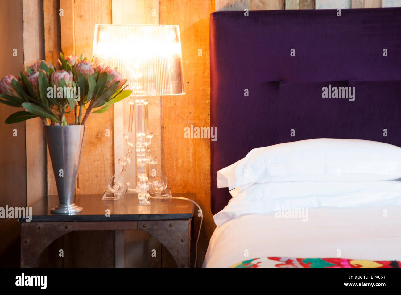 Alessi-Lampe auf Eisen Bett Tisch mit Vase des Königs Proteas in South African home Stockfoto