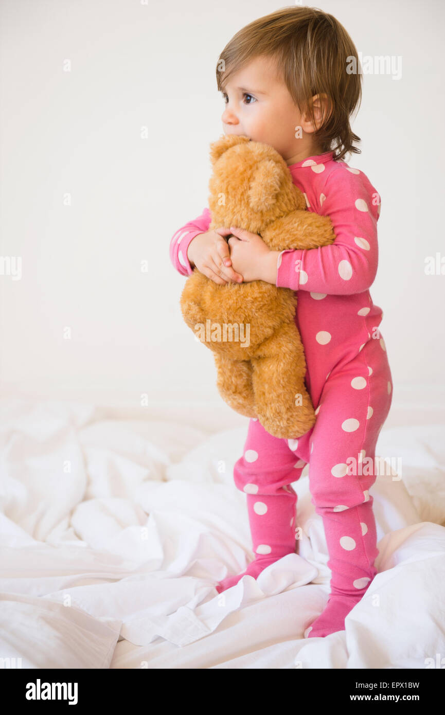 Mädchen (2-3) umfassende Teddybär auf Bett Stockfoto