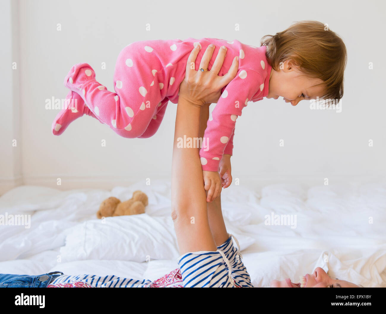 Mutter (2-3) auf Bett mit Mädchen spielen Stockfoto