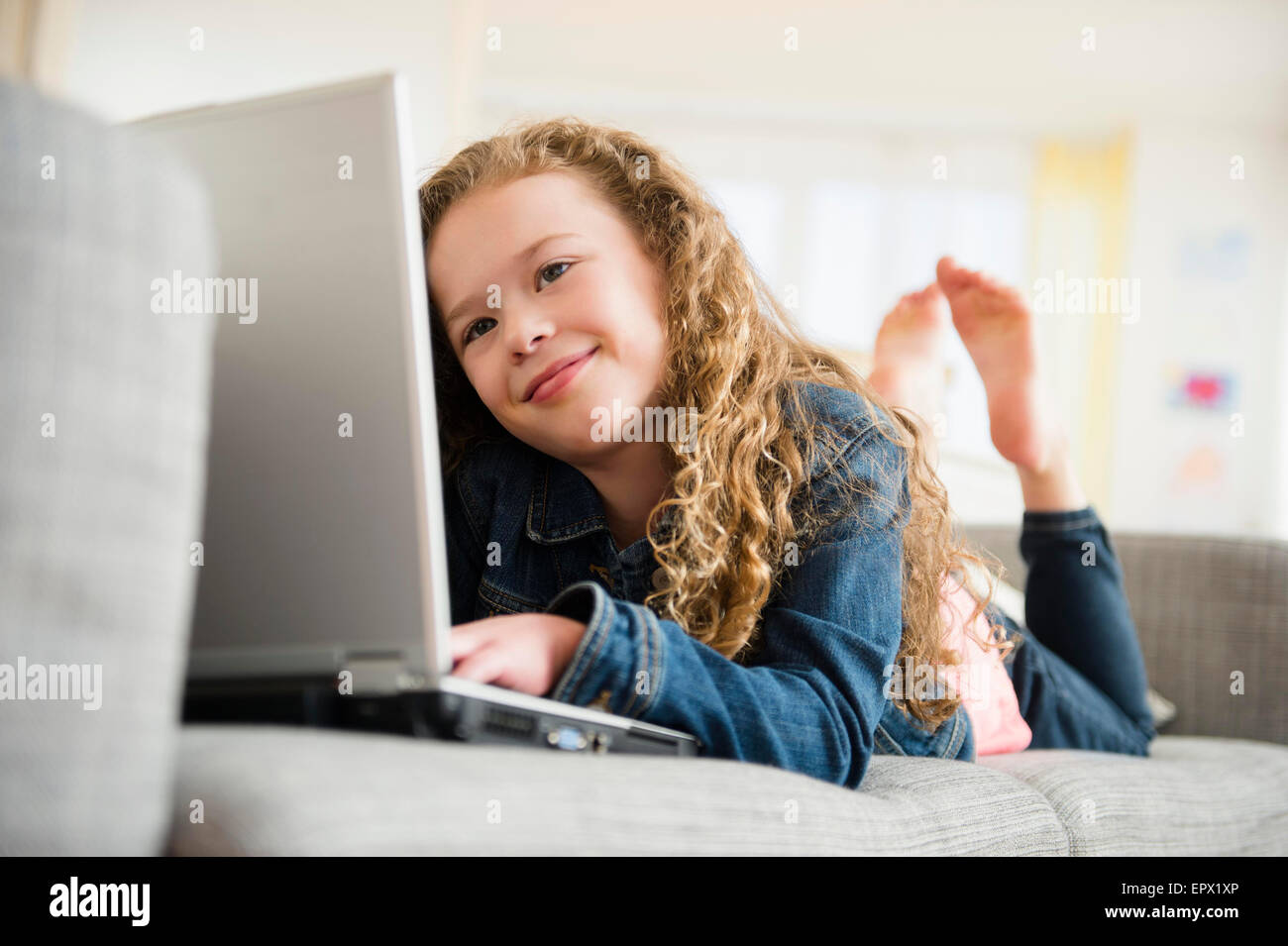 Mädchen (10-11) mit Laptop auf dem Sofa liegend Stockfoto