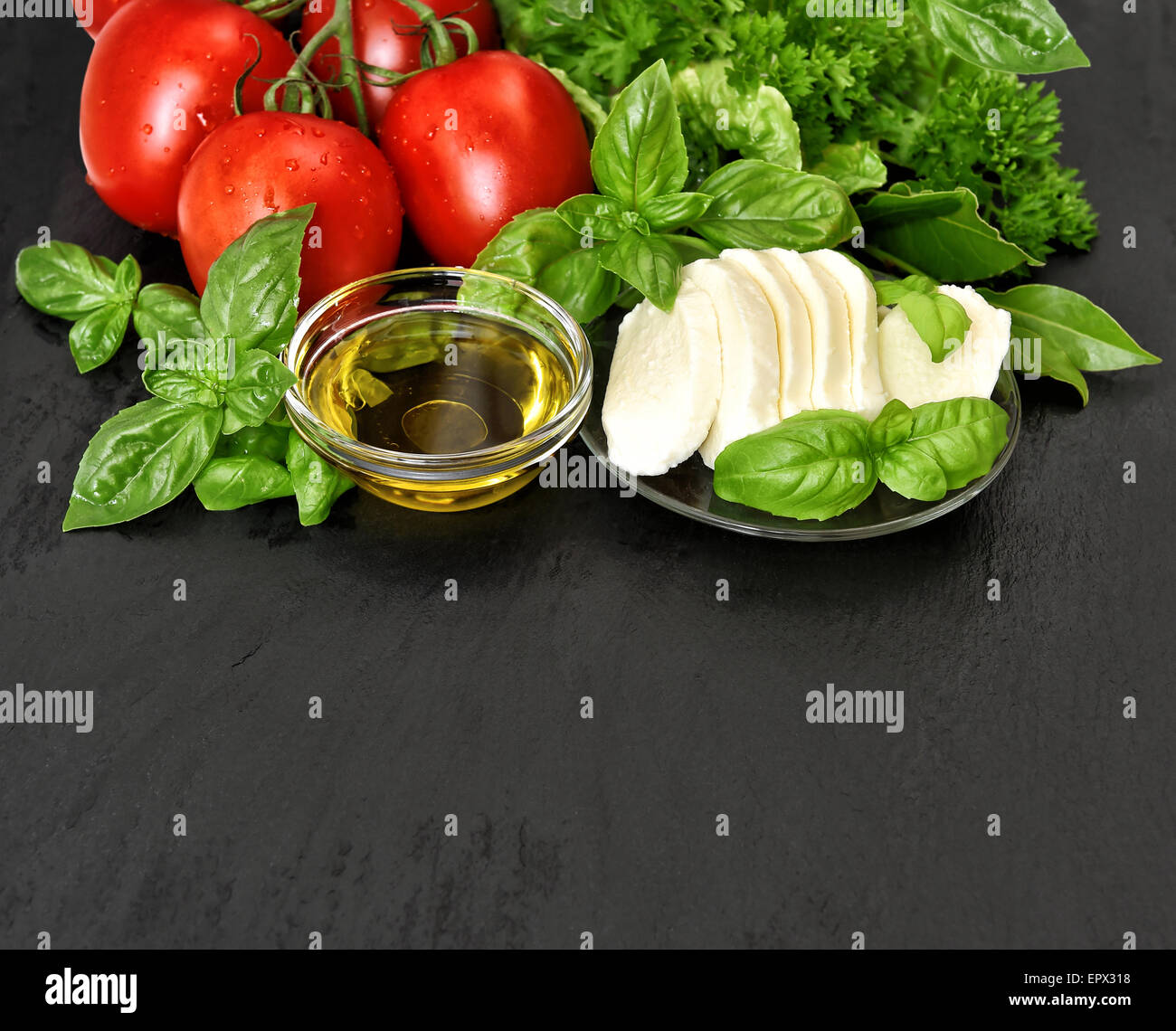 Caprese Salatzutaten. Frischem Basilikum, Tomaten, Mozzarella und Olivenöl auf schwarzem Hintergrund Stockfoto