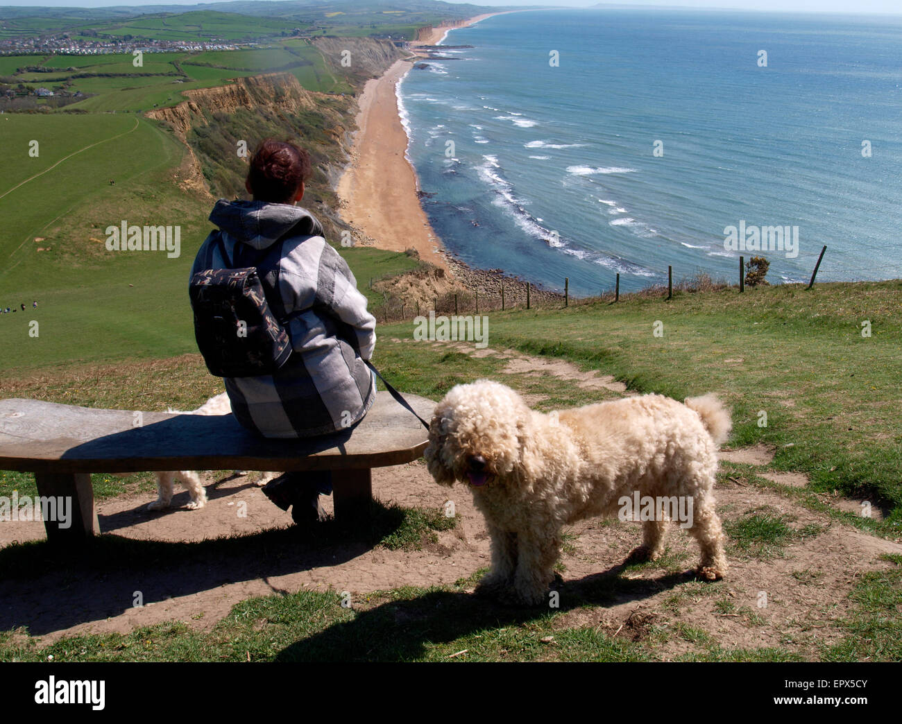 Frau saß auf einer Bank auf dem Thorncombe Beacon Hill mit Blick auf Eype, Dorset, Großbritannien Stockfoto
