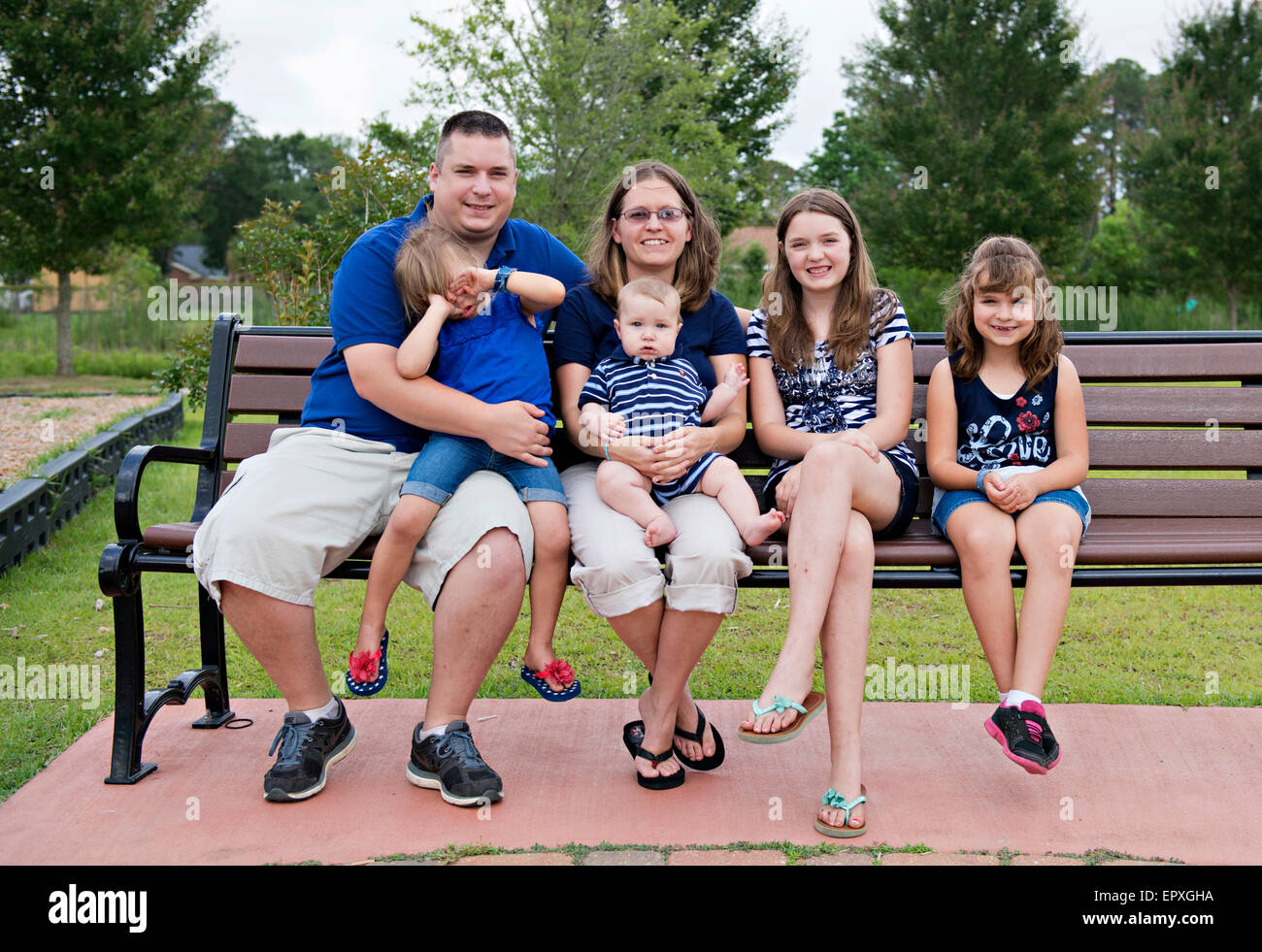 Familie posieren für ein Porträt in ein Outdoor-Spielplatz-Parkbank Stockfoto