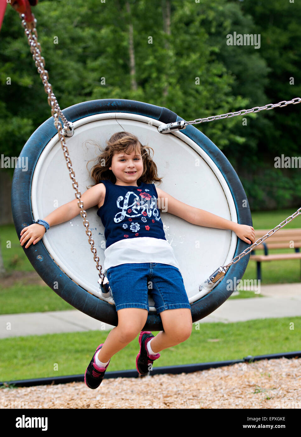 Junges Mädchen schwingt auf einer Untertasse Schaukel auf einem Spielplatz park Stockfoto