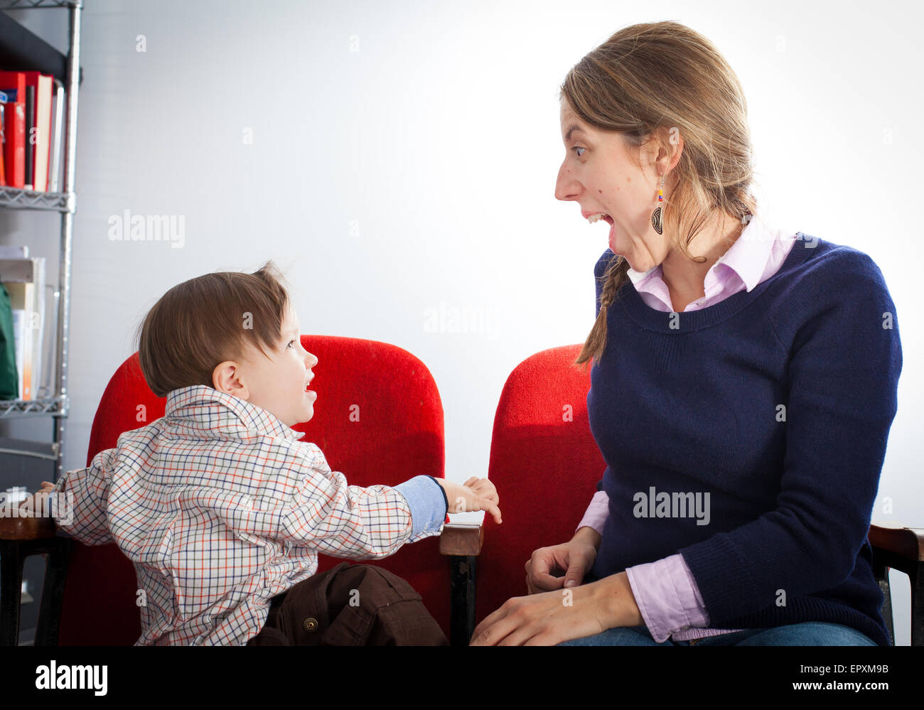 Frau und ihr Sohn sitzen auf Stühlen und spielen Stockfoto