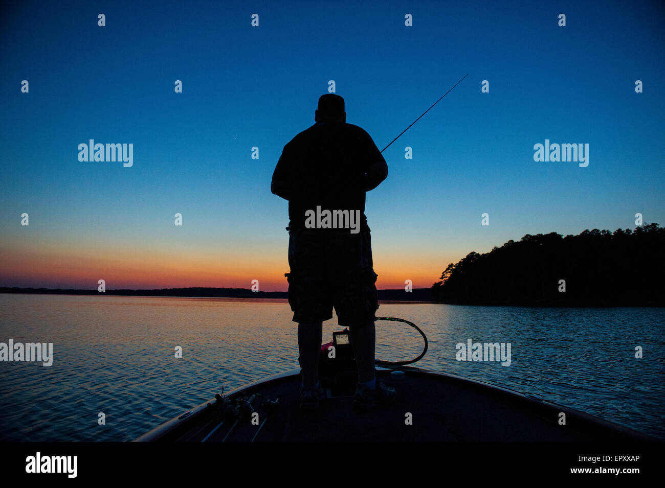 Fischer am Bug des Bass Boot Angeln bei Sonnenuntergang für forellenbarsch McGee Creek Lake in Oklahoma. Stockfoto