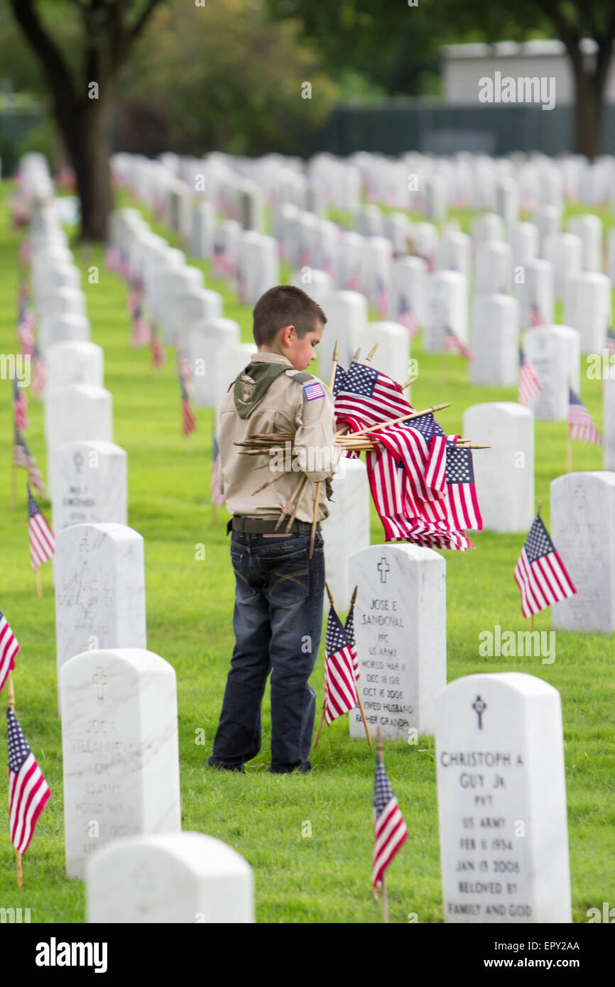 Ein Pfadfinder stellt die amerikanische Flaggen in Grabstätten bei Memorial Day Vorbereitungen in Fort Sam Houston National Cemetery Stockfoto