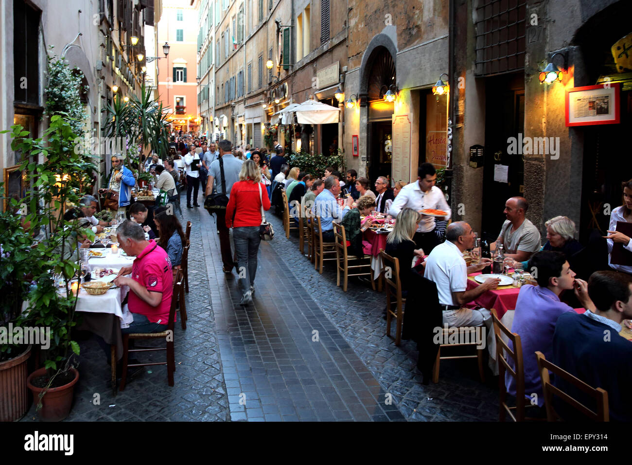 Menschen Essen in einer kopfsteingepflasterten Gasse in Rom. Stockfoto