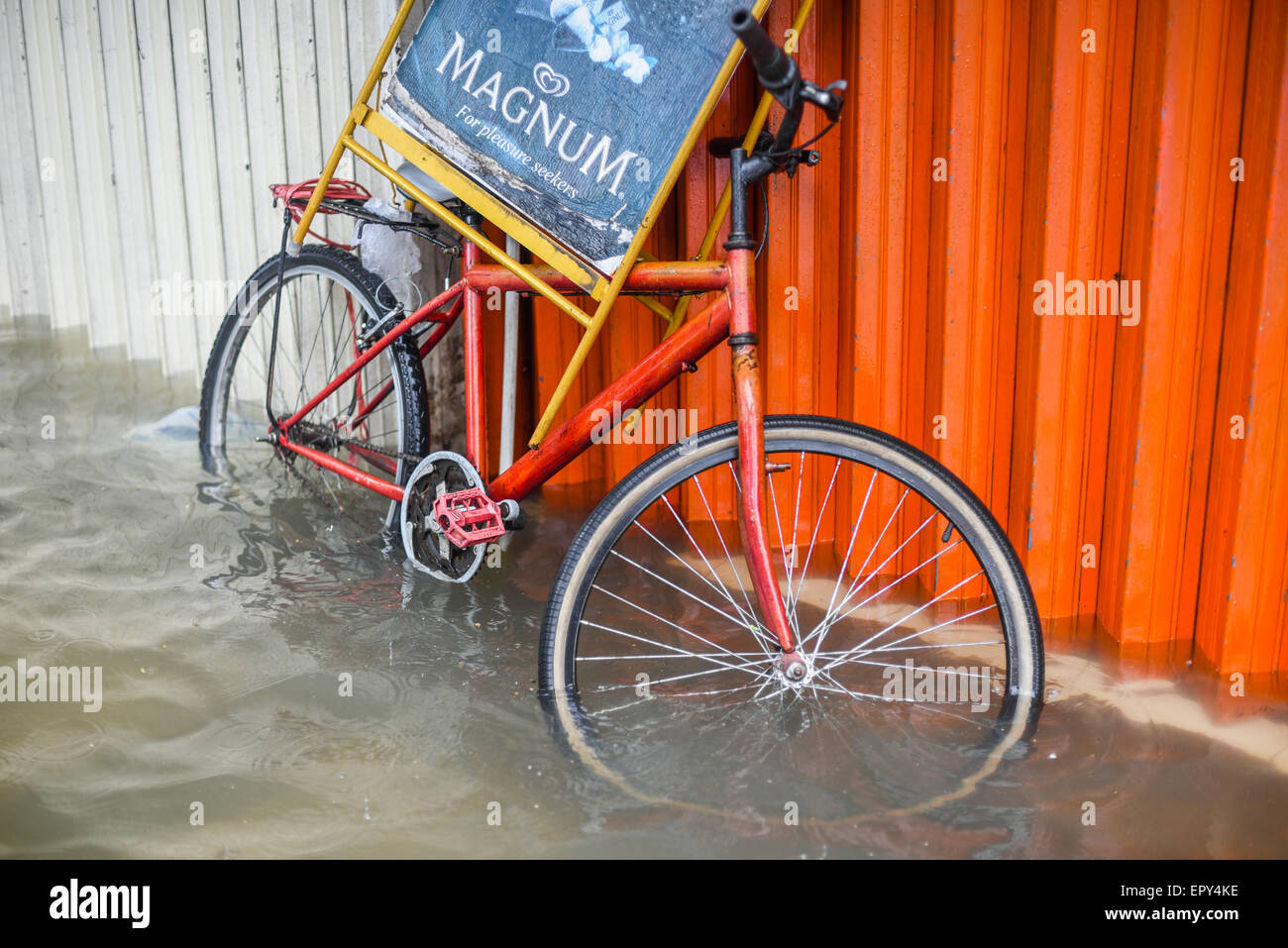 Ein Werbefahrrad, das an der Außenwand des Ladens in einem überfluteten Bereich geparkt wurde, verließ nach einem anhaltenden Regen das Stadtzentrum von Jakarta überflutet. Stockfoto