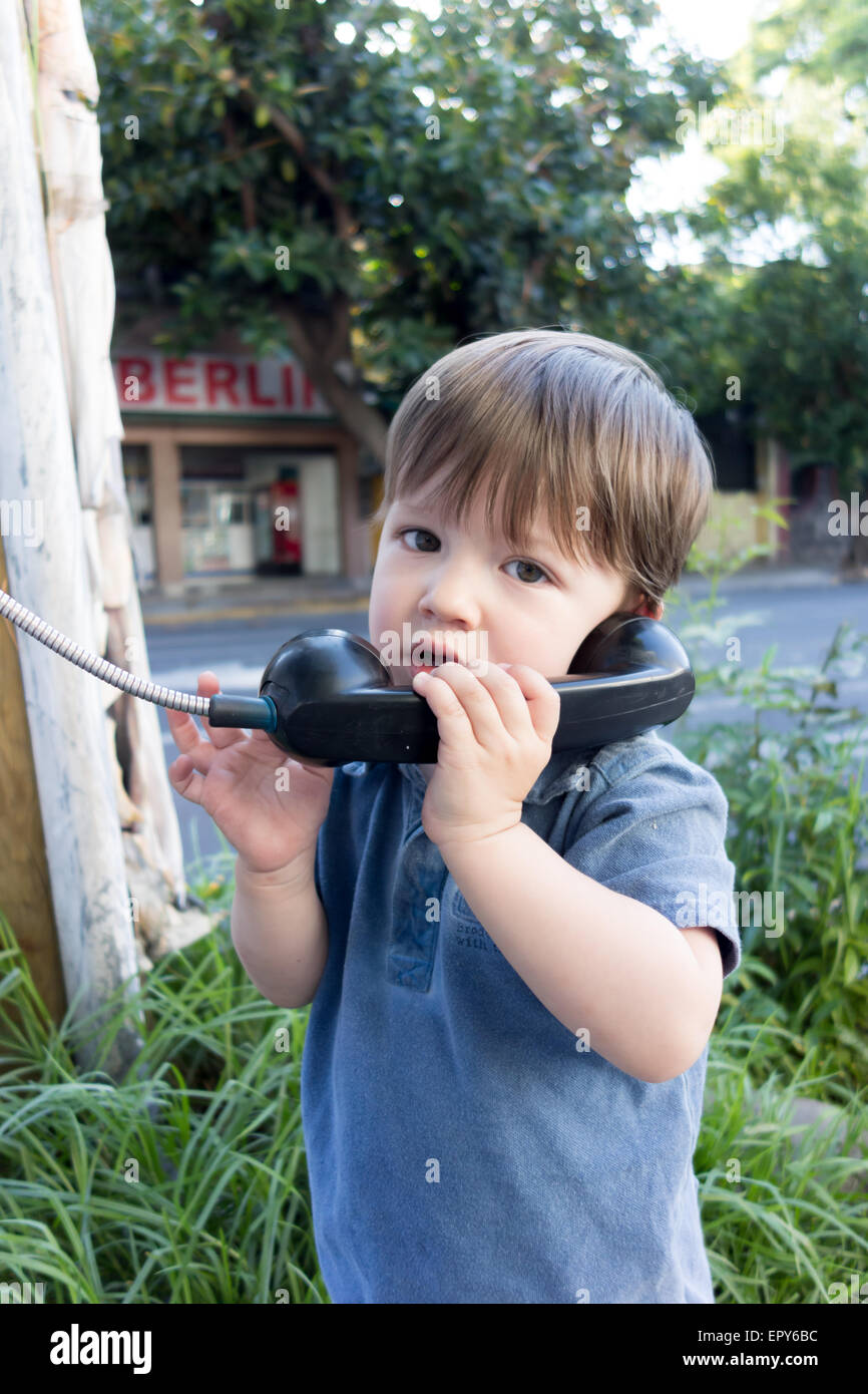 Porträt eines Kindes mit einem öffentlichen Telefon Stockfoto