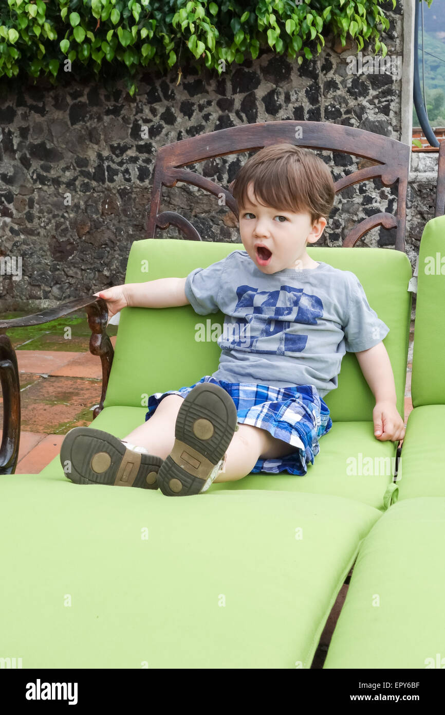 Junge sitzt auf einem Liegestuhl und Gähnen Stockfoto