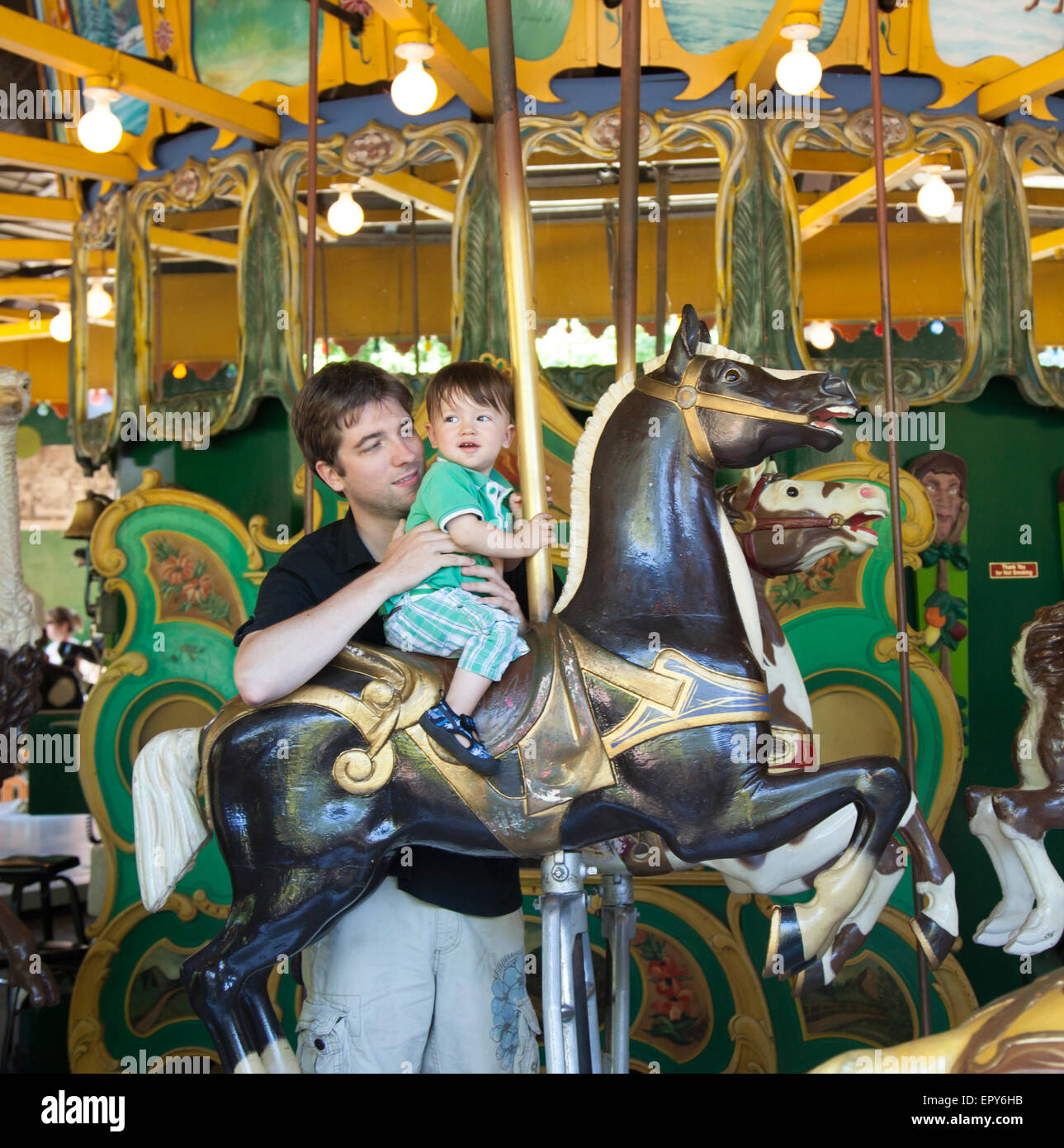 Mann genießt Karussellfahrt mit seinem Sohn Stockfoto