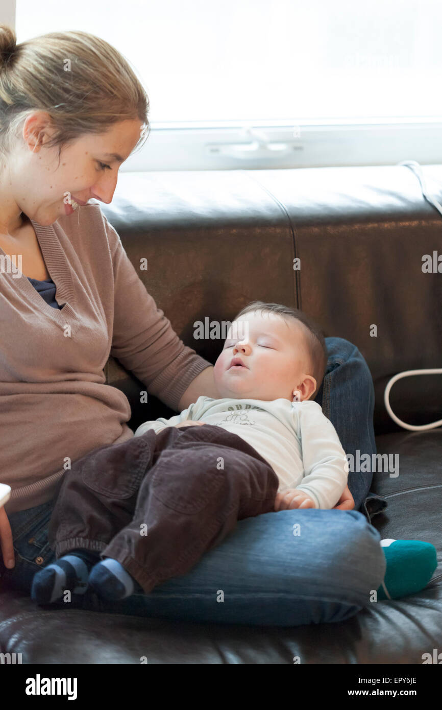 Babyjungen in den Schoß seiner Mutter schlafen Stockfoto