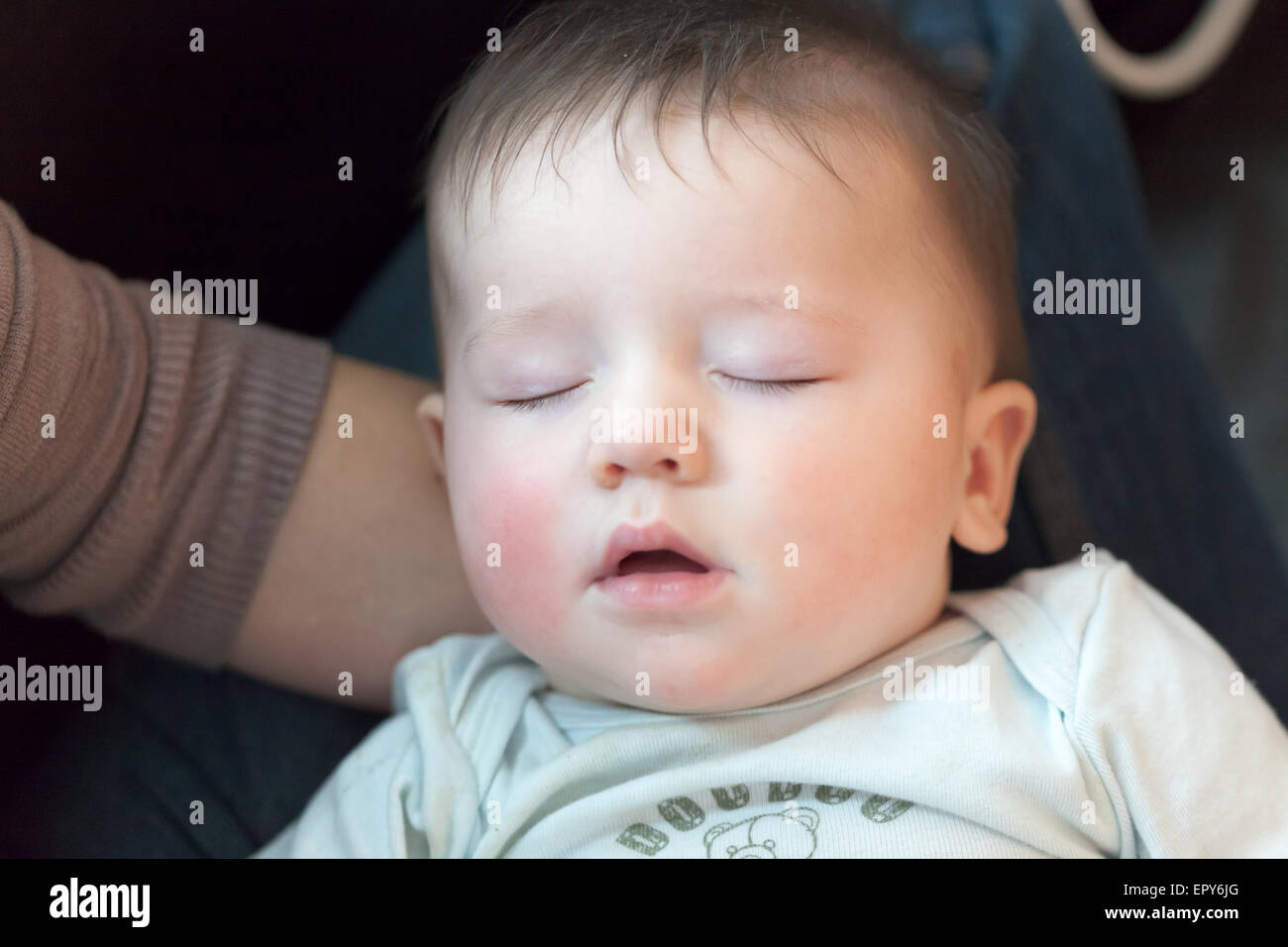 Babyjungen in den Schoß seiner Mutter schlafen Stockfoto