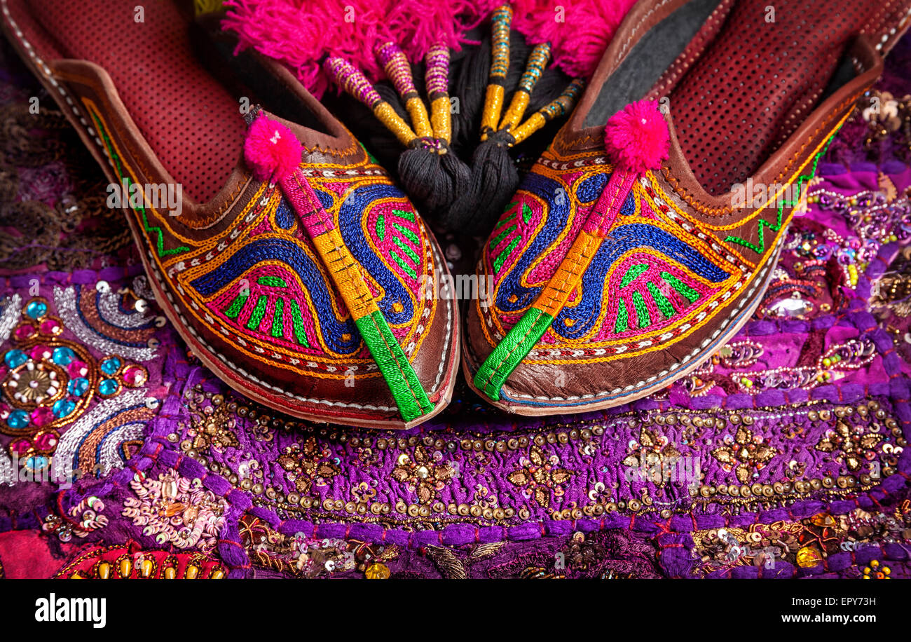 Bunten ethnischen Schuhe und Kamel Dekorationen auf violetten Kissenhülle aus Rajasthan am Flohmarkt in Indien Stockfoto