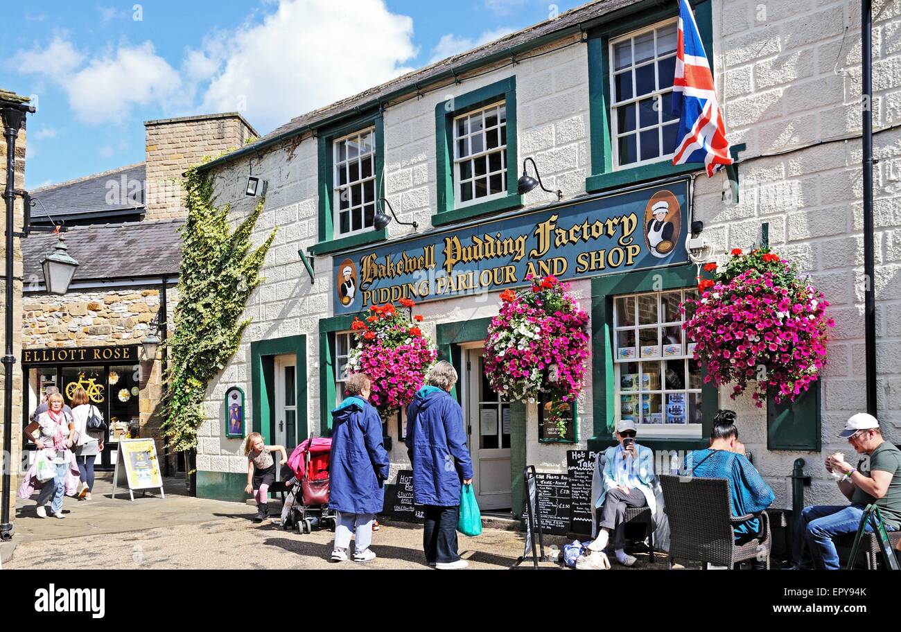 Touristen sitzen in einem Straßencafé außerhalb der Bakewell Pudding Fabrik im Zentrum Stadt, Bakewell, Derbyshire, England, Vereinigtes Königreich, Stockfoto