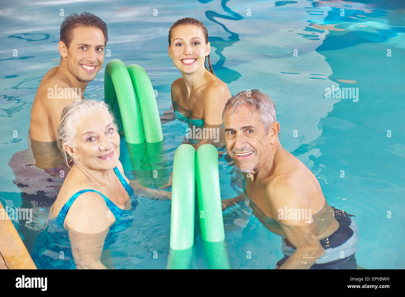 Zwei glückliche Paare in Aqua-Fitness-Klasse in einem Schwimmbad mit Schwimmen Nudeln Stockfoto